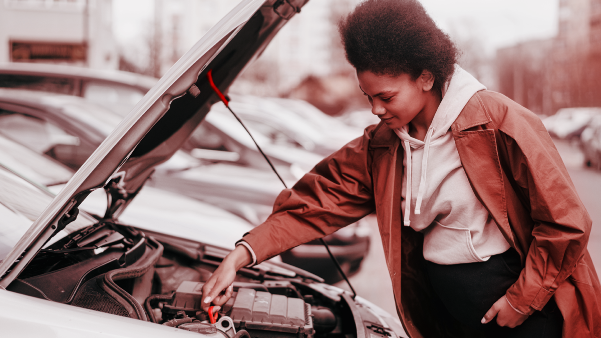 Mulher verificando o óleo do carro com o capô aberto.